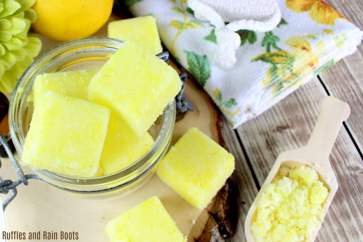 bright yellow squares of lemon sugar scrub in a sealed hermetic jar for the bathroom with a wood round and a sprinkle of bath scrub in a small wood spoon 