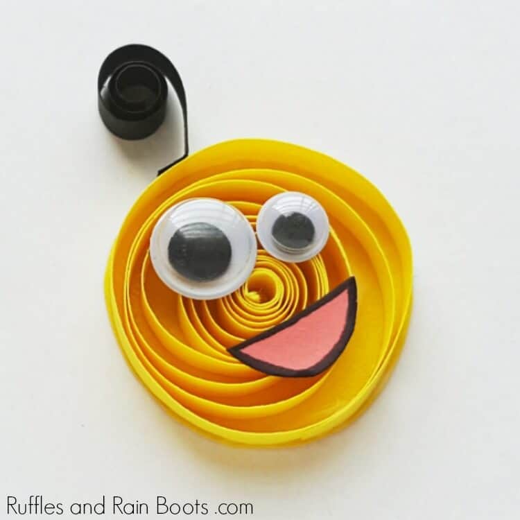yellow quilled monster craft with googly eyes and a smiling mouth on a white background