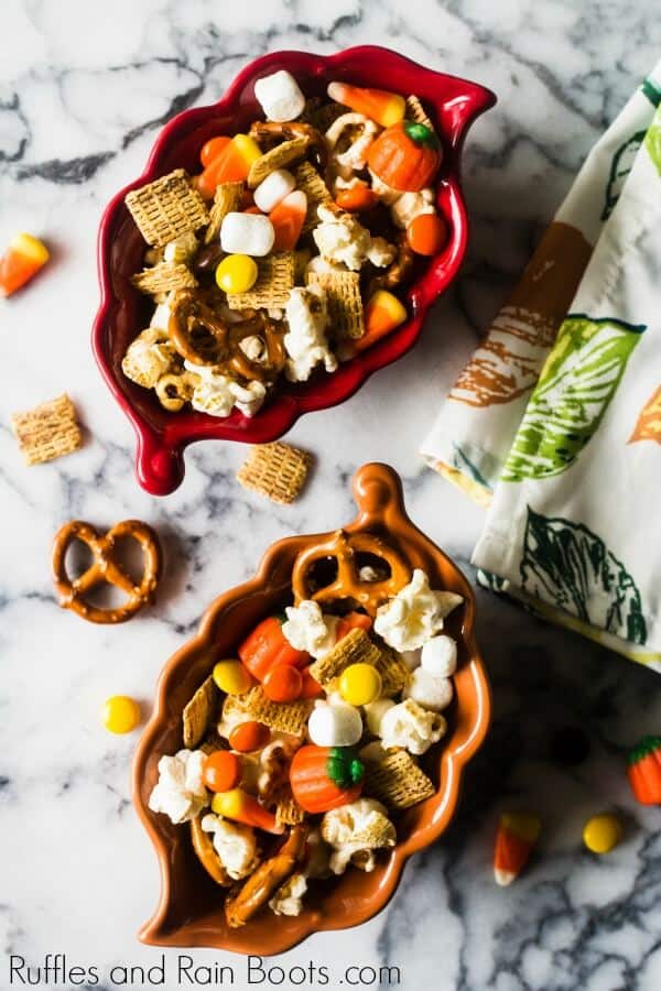 two leaf bowls full of fall autumn snack mix on a marble table with a kitchen towel