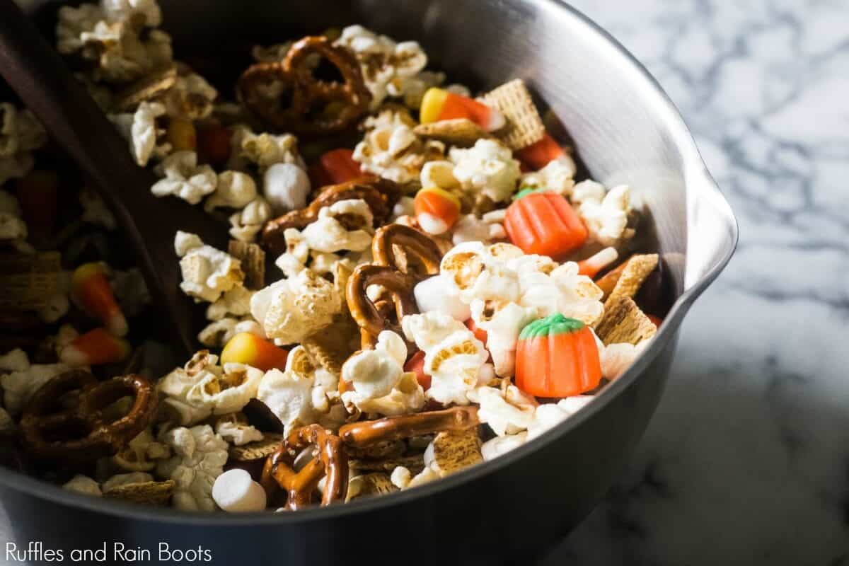 large bowl and spoon mixing together a sweet and salty popcorn fall snack mix