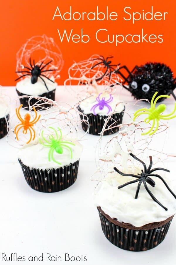 cupcakes with white frosting, sugar spider webs, and plastic spiders on a white and orange background with text which reads Adorable Spider Web Cupcakes