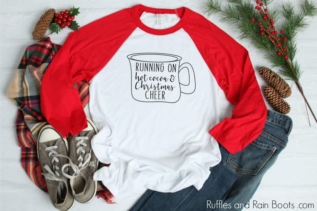 red raglan t shirt on Christmas background with mug drawing and text which reads Running on Hot Cocoa and Christmas cheer
