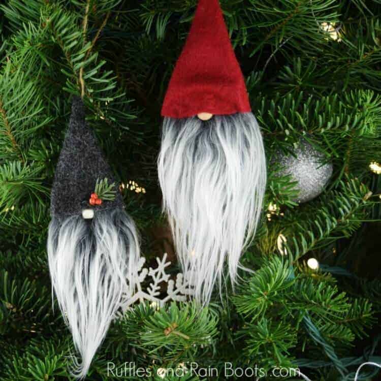 Vertical image of two no sew gnome ornaments hanging on lighted Christmas tree.