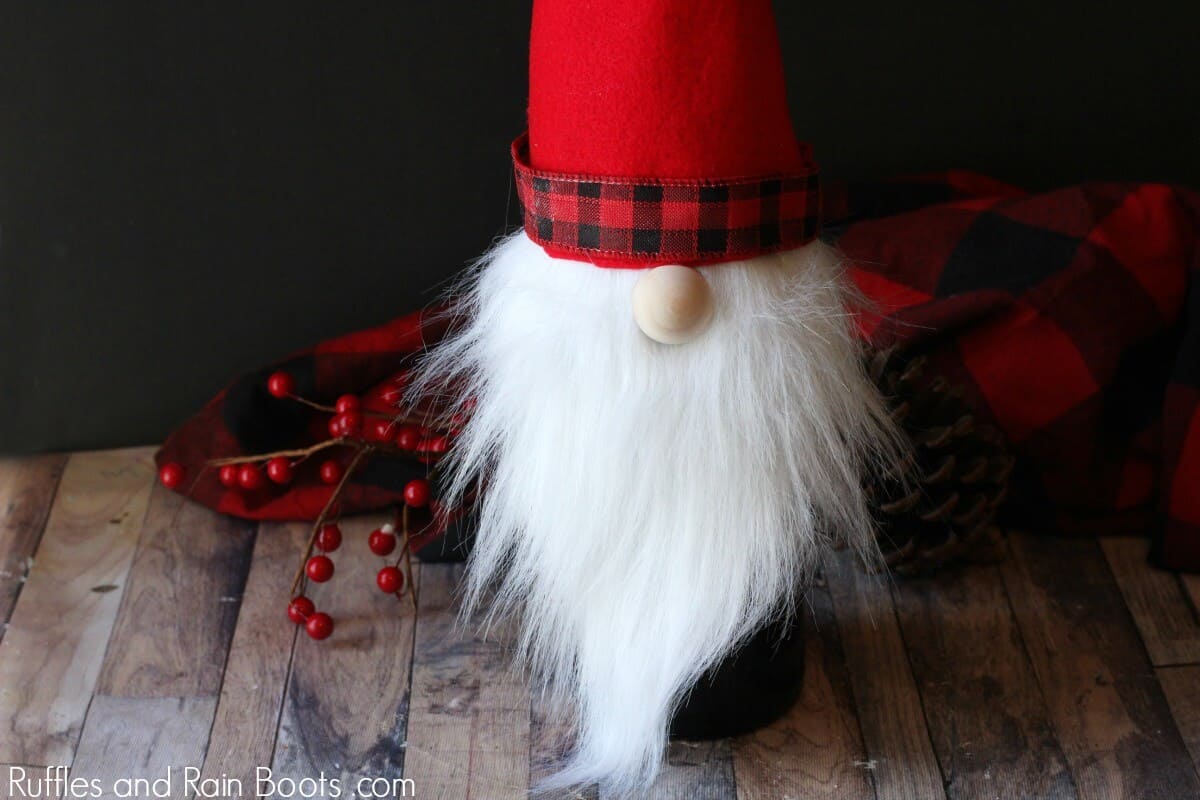 A red hat and white beard Christmas gnome wine bottle cover on holiday background.