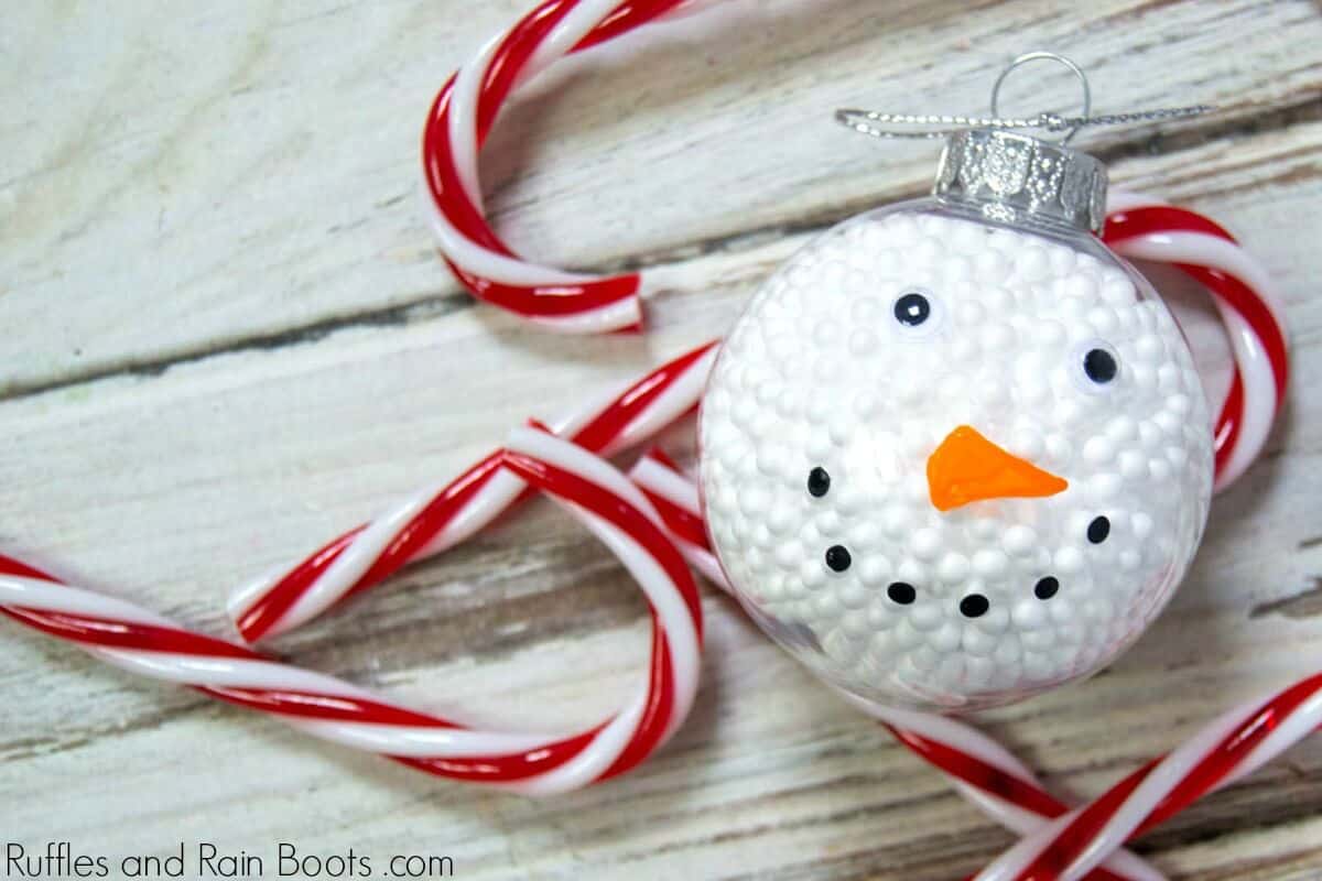 Easy Snowman Ornament on wood background with candy canes