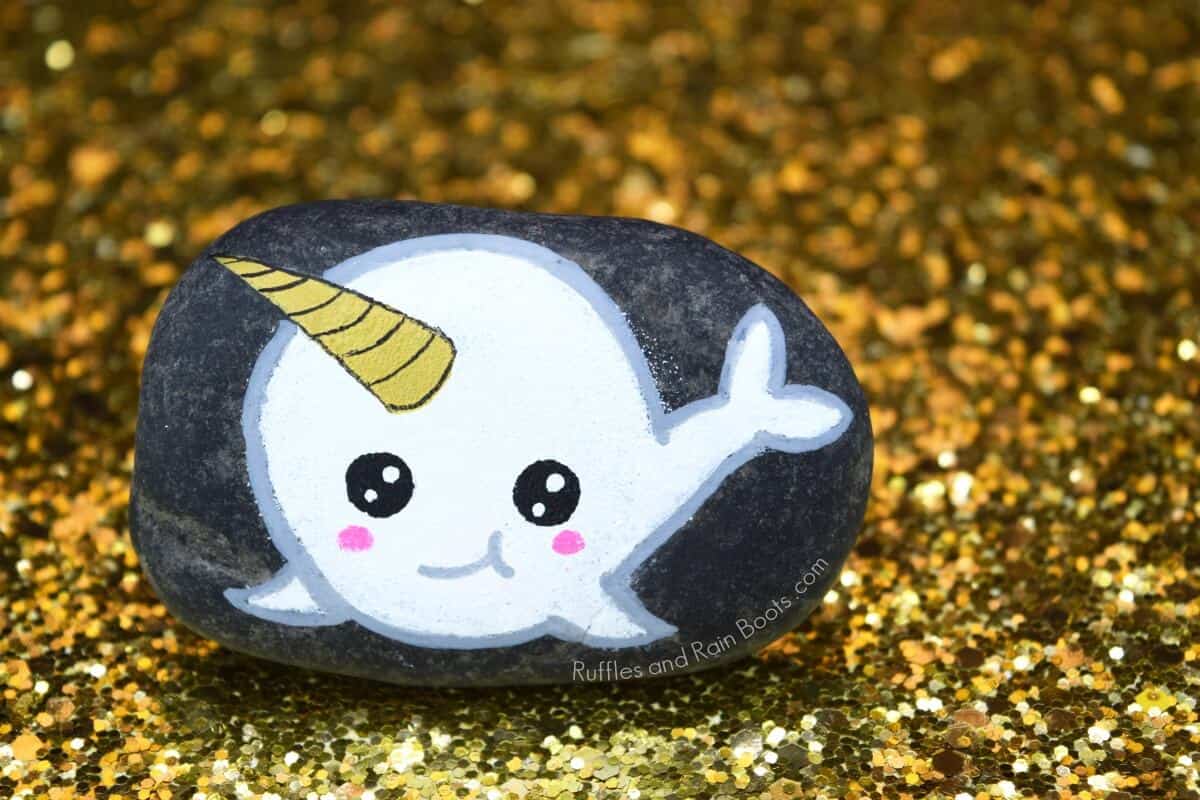 narwhal rock painting on gold glitter background