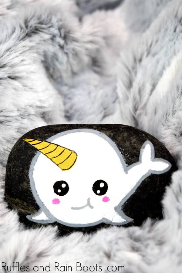 white narwhal rock painting on dark stone with a fuzzy gray background