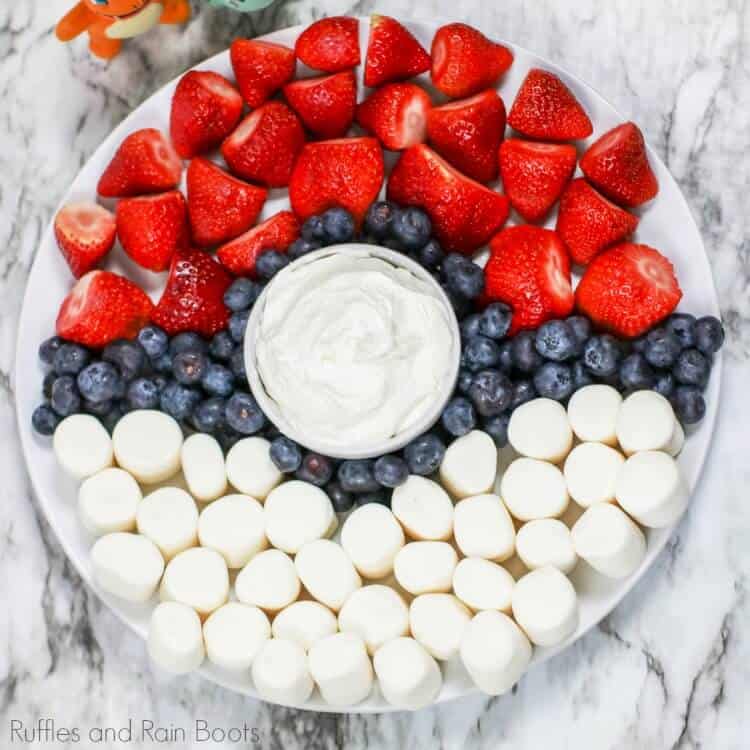 Overhead view of strawberries, bananas, blueberries and dip arranged on a tray to look like a pokemon pokeball fruit tray.