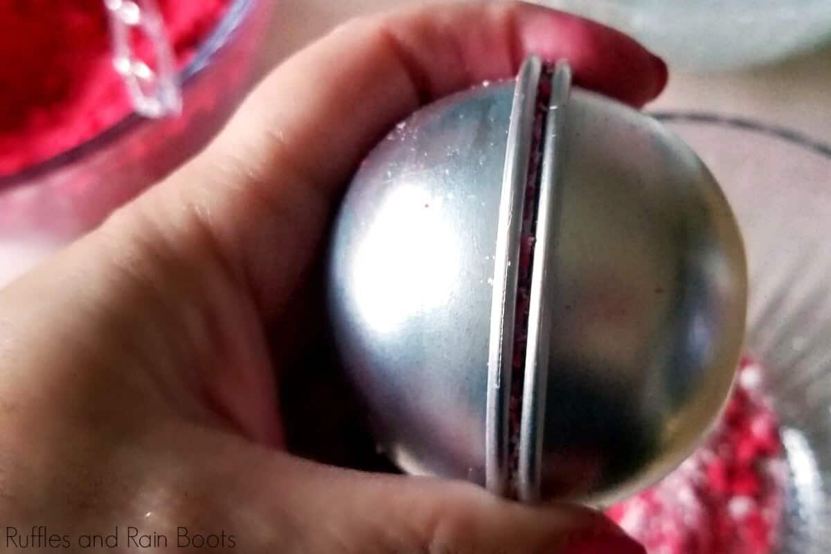 in-process step of molding a snow white bath bomb in a silver mold in a hand