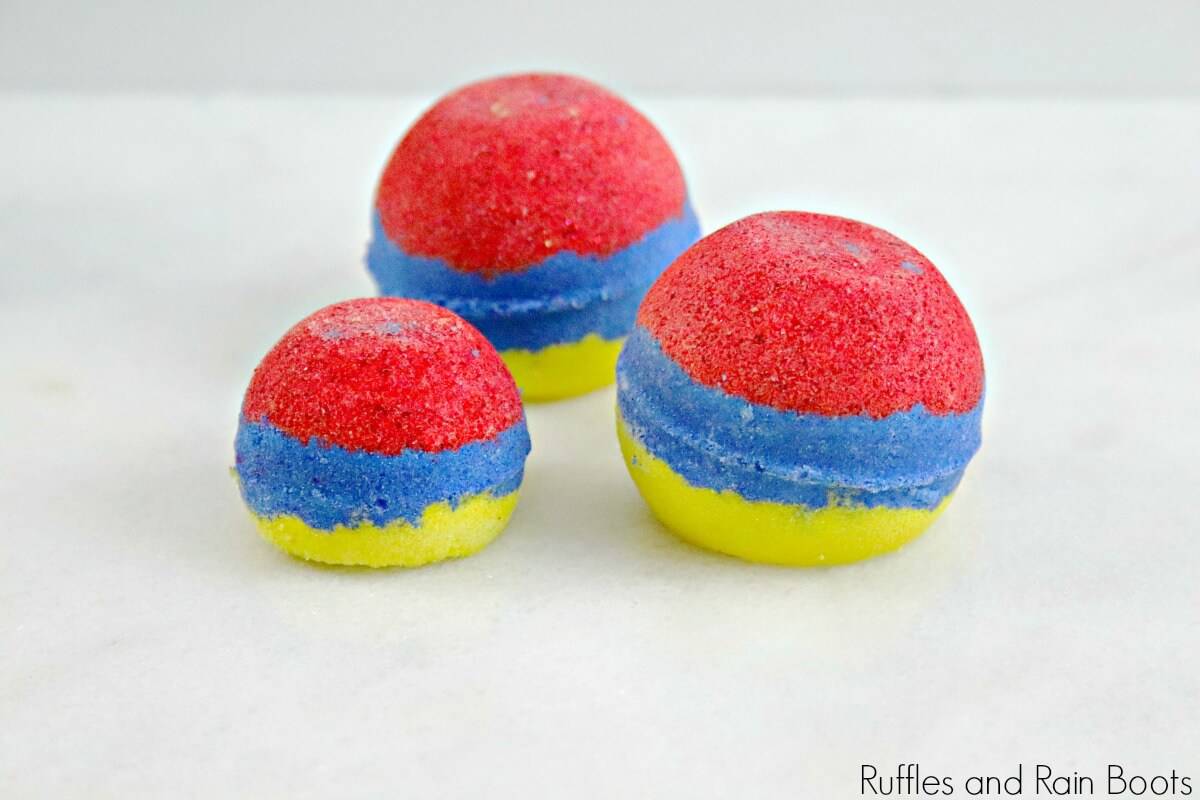 side view of red, blue and yellow Snow White bath bombs on a white background