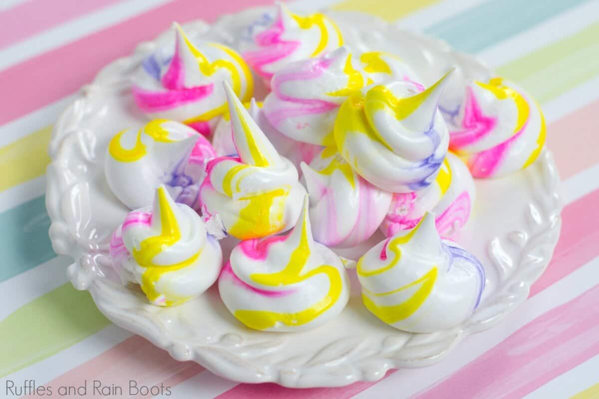 unicorn meringues on white plate on pink background