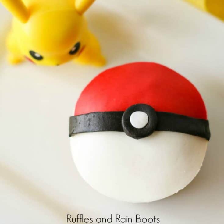top-down view of a finished pokeball cupcake with pikachu figurine on a white background