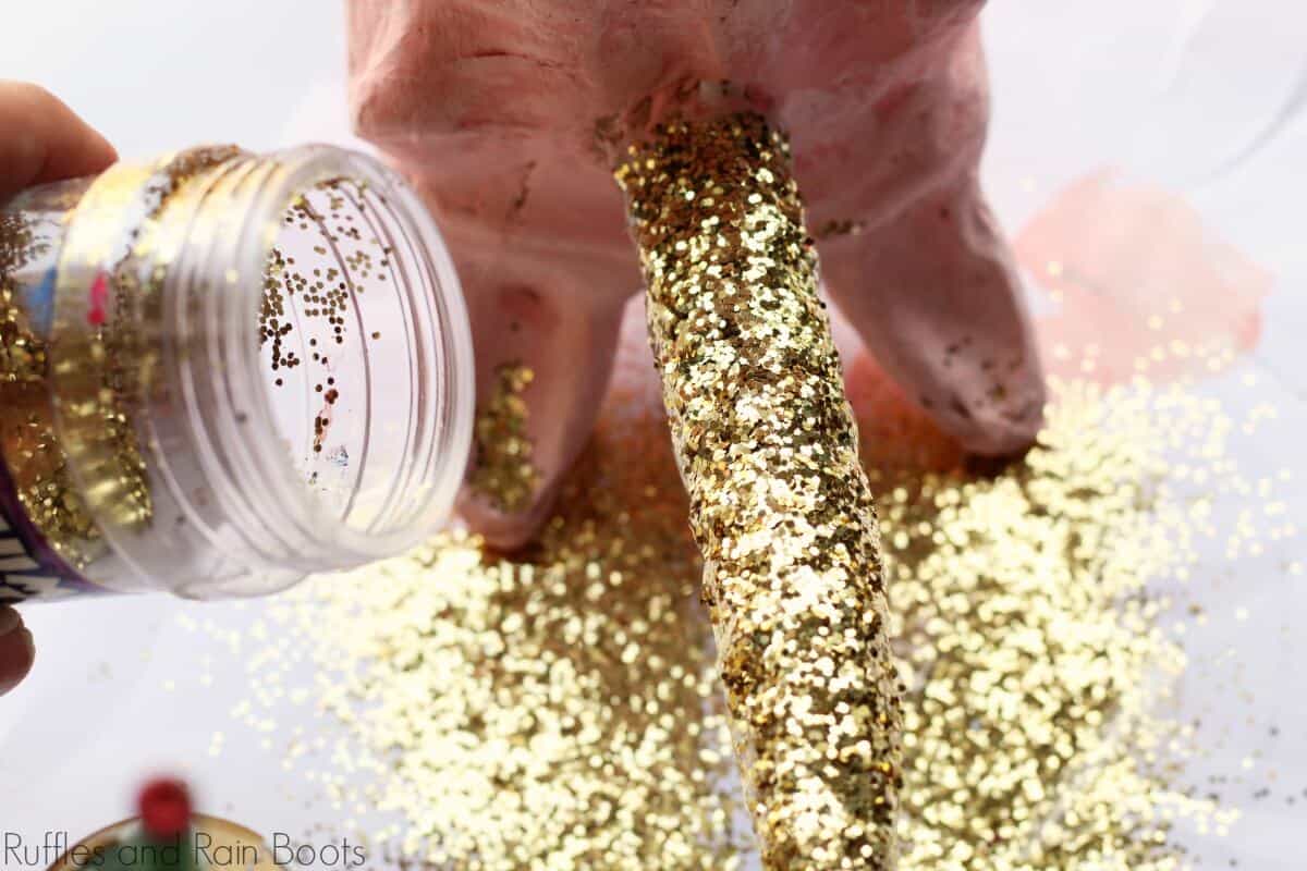adding glitter to the unicorn head decor and shaking off the excess glitter