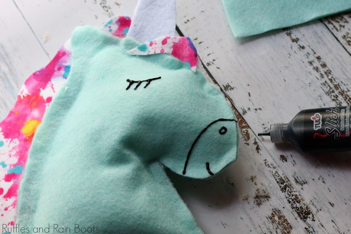 adding eyes to the unicorn pillow with puffy paint