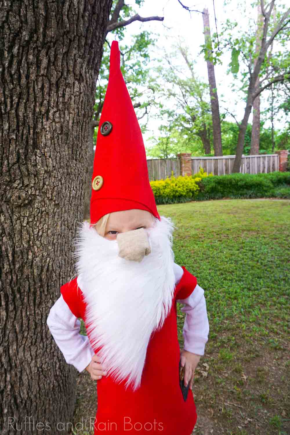 Adorable child standing in a yard and dressed in a felt DIY gnome hat and gnome costume made for kids.