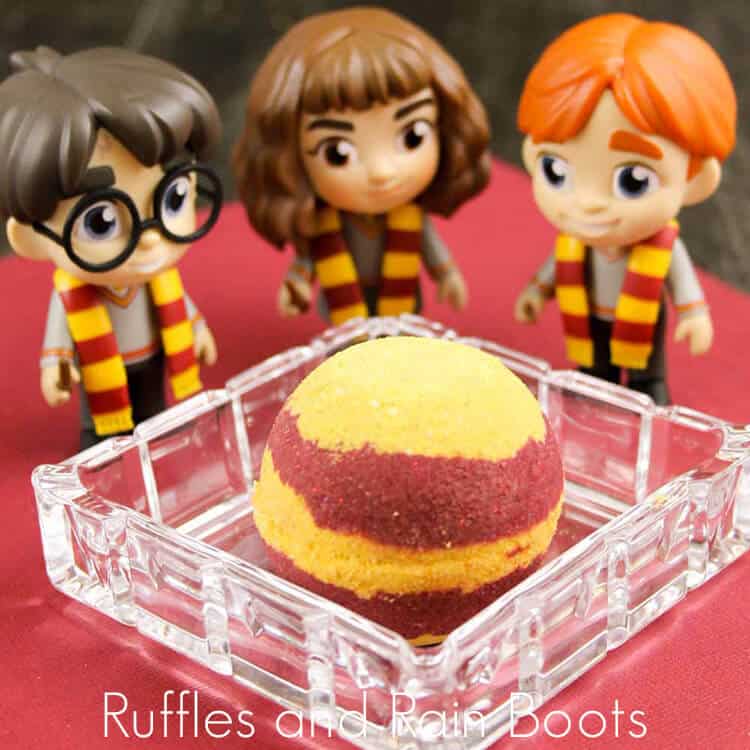griffindor bath bombs in a clear dish with harry potter movie figurines on a red background