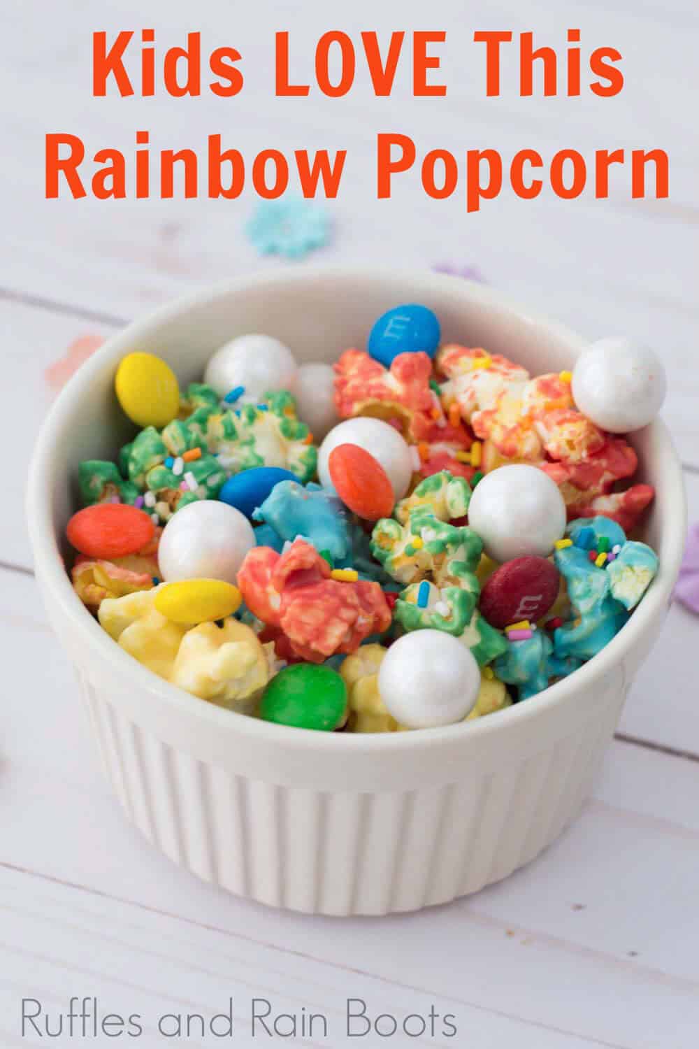 easy candy popcorn recipe for multi-colored popcorn in a white bowl with text which reads kids love this rainbow popcorn