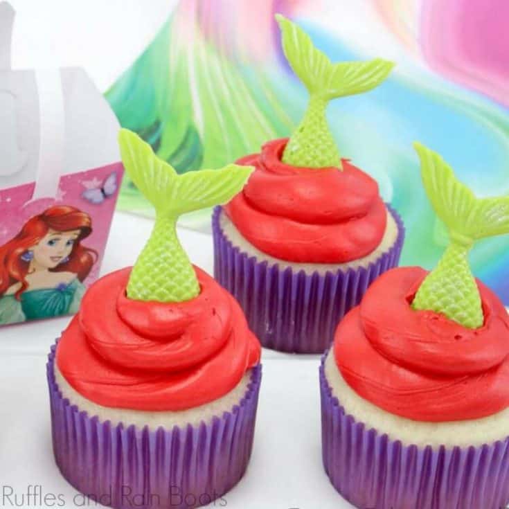 mermaid cupcakes with green tails, red icing and purple liners on a white background