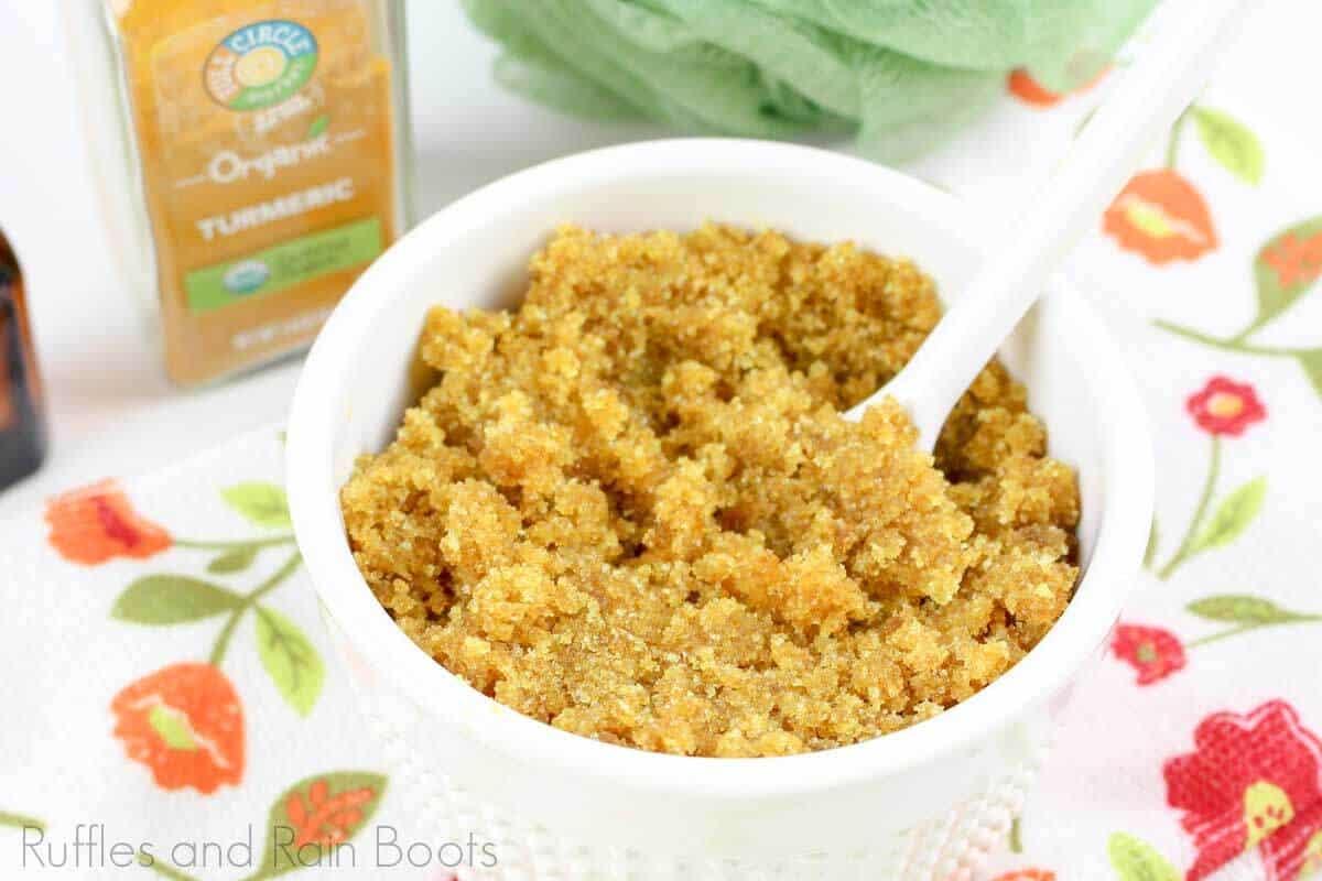 turmeric sugar scrub for healthy skin in a white bowl on a floral background
