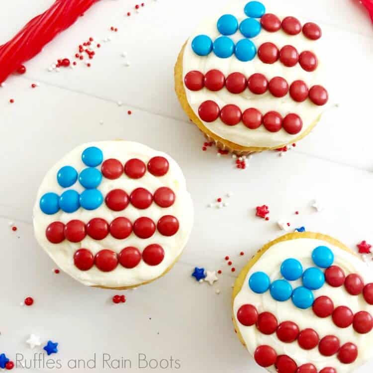 overhead view of 3 flag cupcakes, white cupcakes decorated with a flag made of candy, on a white background