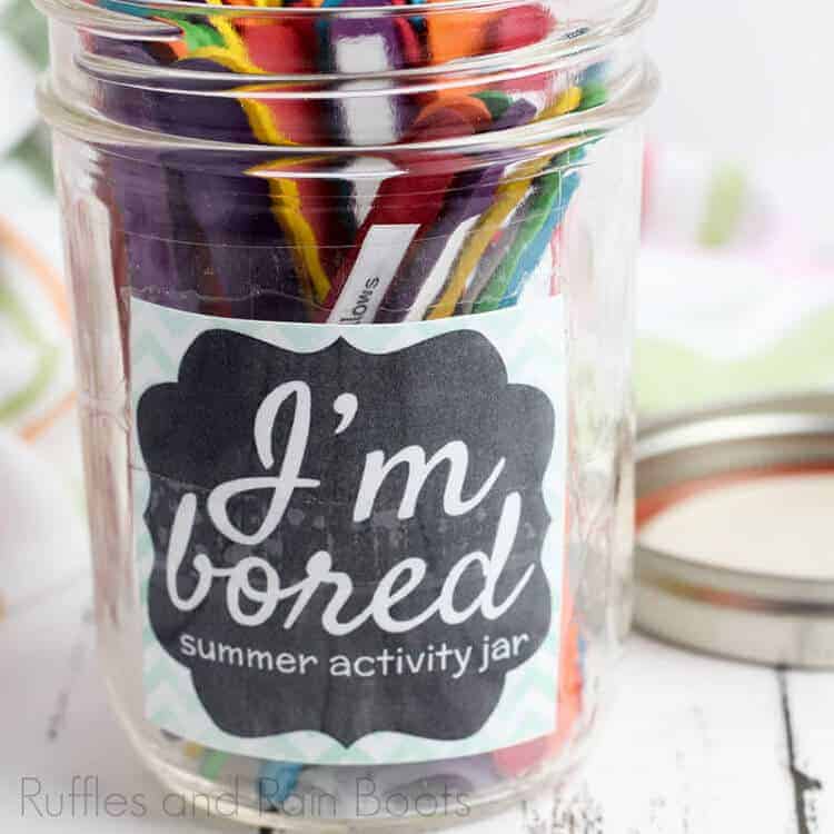 I'm bored jar for summer activity for kids on a wooden white table with lid laying nearby