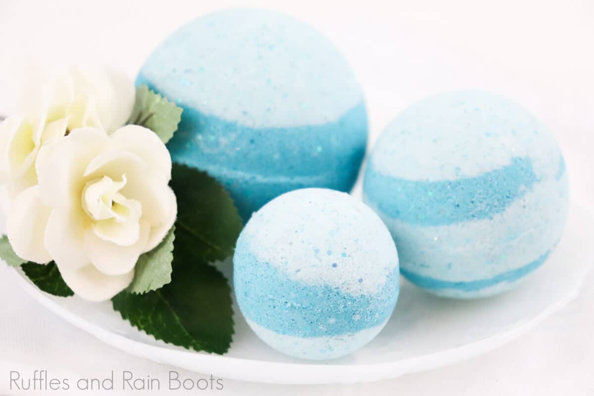 side view of simple princess jasmine bath bomb recipe sitting on a white bowl with a flower on a white background