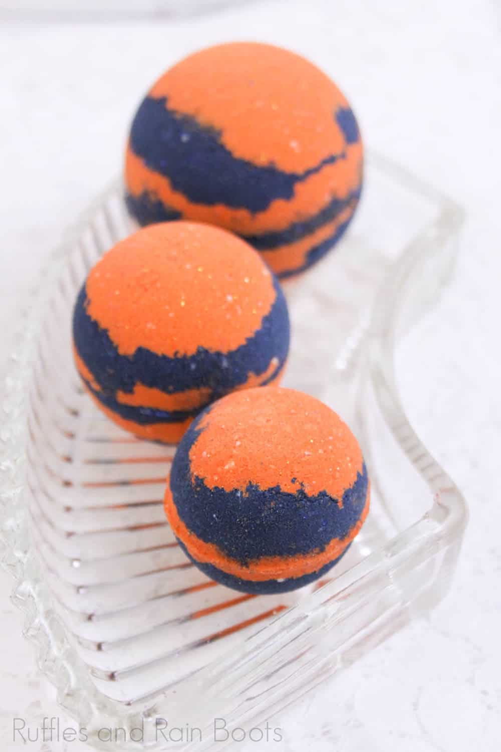 three bright orange and blue bath bombs on a glass plate on a white table to represent adorable merida bath bombs inspired by disney