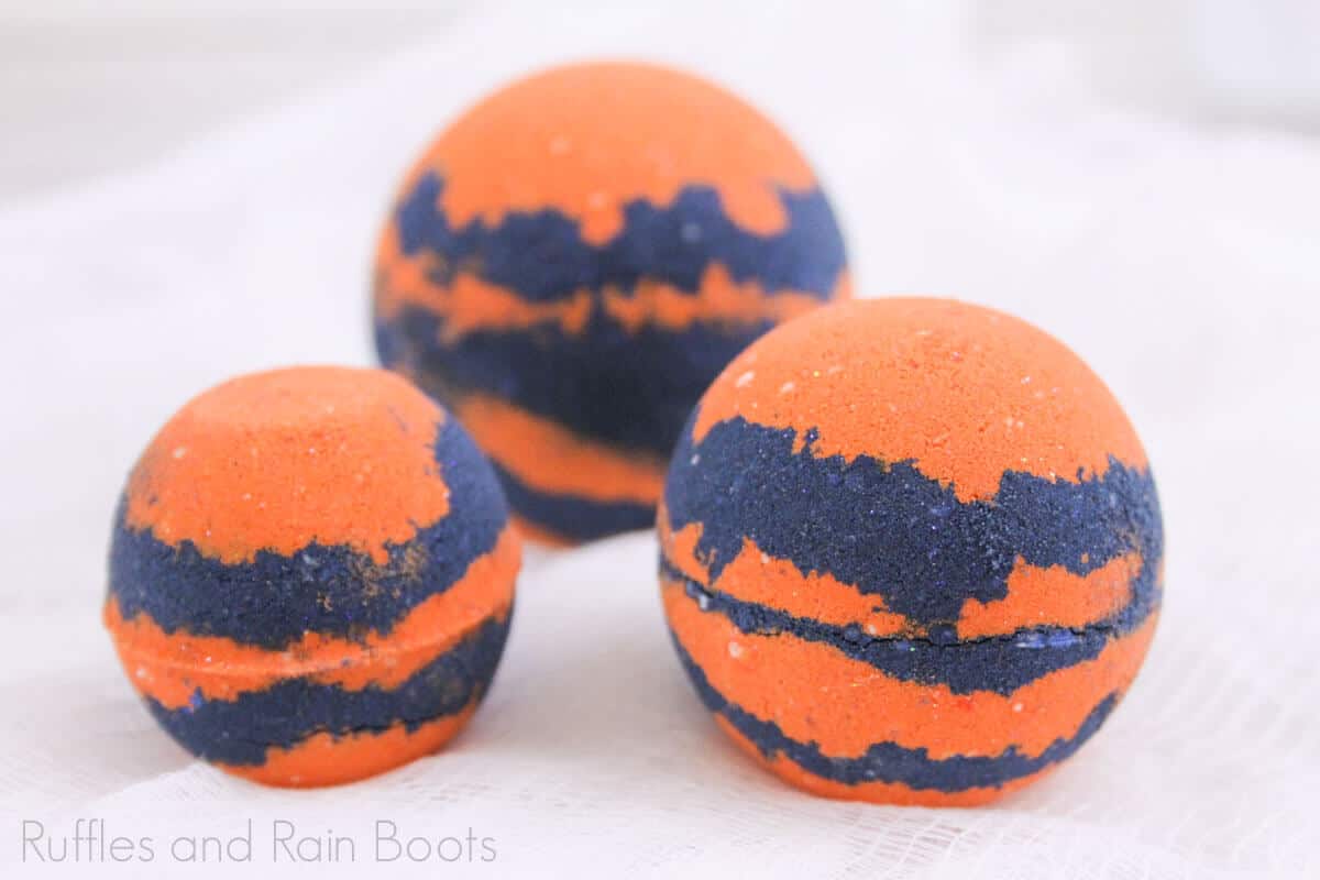 three bright orange and blue princess merida bath bombs recipe on a white table with a white background