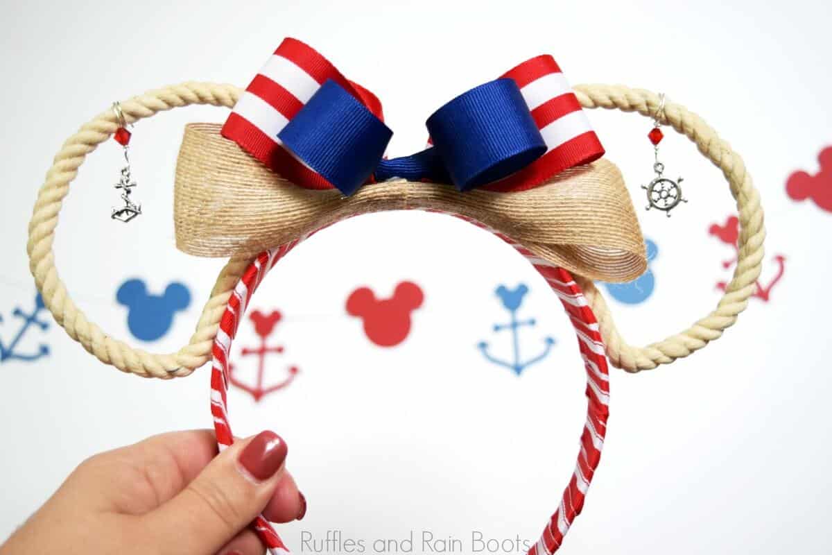 hand holding adorable Disney cruise ears with open rope ears and nautical charms on white background