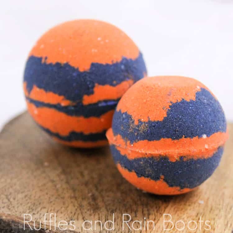 two bright orange and blue princess merida bath bombs on a wood table on a white background