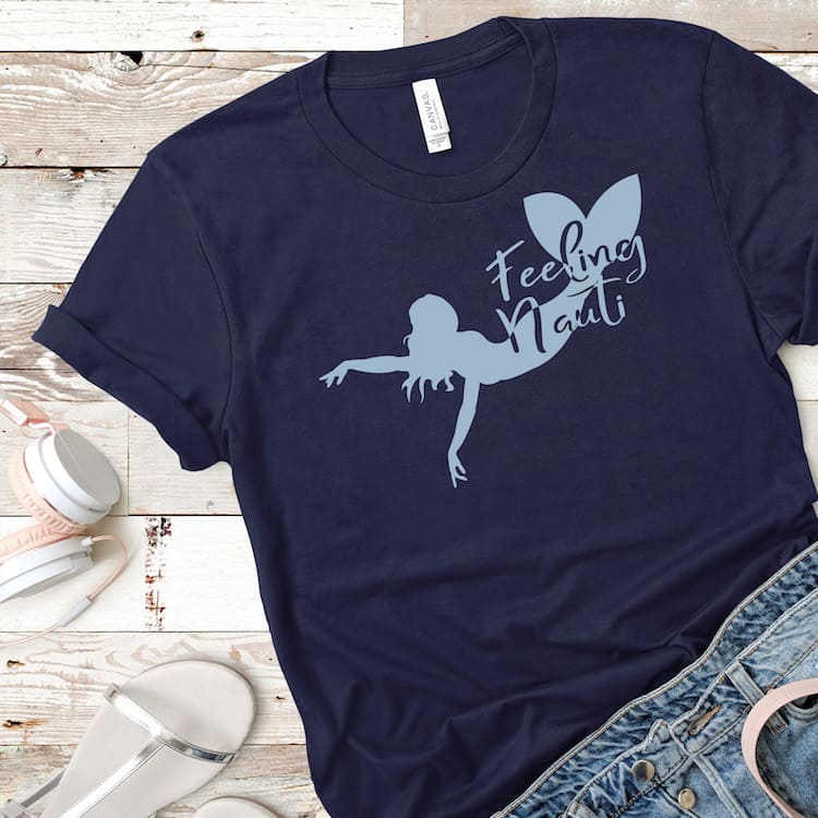 feeling nauti mermaid cut file for Cricut on blue tshirt on a wood table with jeans and headphones