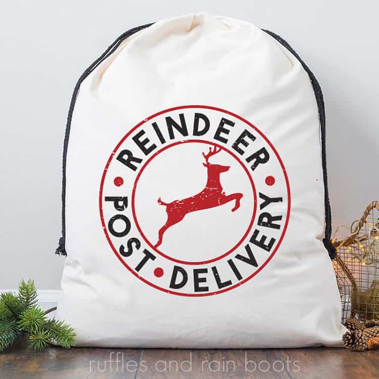 handmade Santa sack gift bag with free Reindeer Delivery Christmas SVG leaning up against the wall next to a Christmas tree