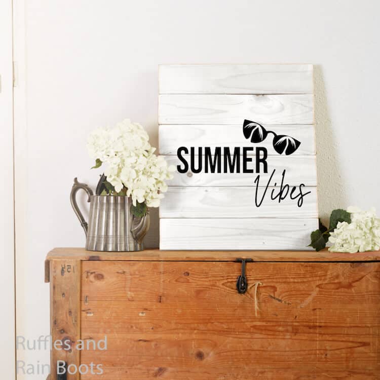 free svg for summer fun Summer Vibes with Palm Tree Sunglasses on Wood Sign on a trunk against a white wall with flowers beside it