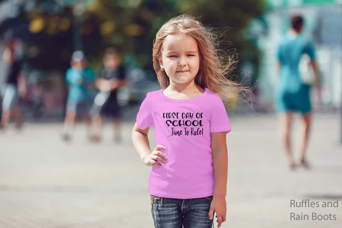 time to rule back to school svg on pink kid shirt worn by a little girl on a street with people in the background