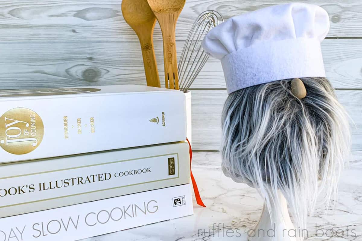 adorable chef gnome made from sock gnome body and handmade chef toque on kitchen background with cookbooks and baking utensils