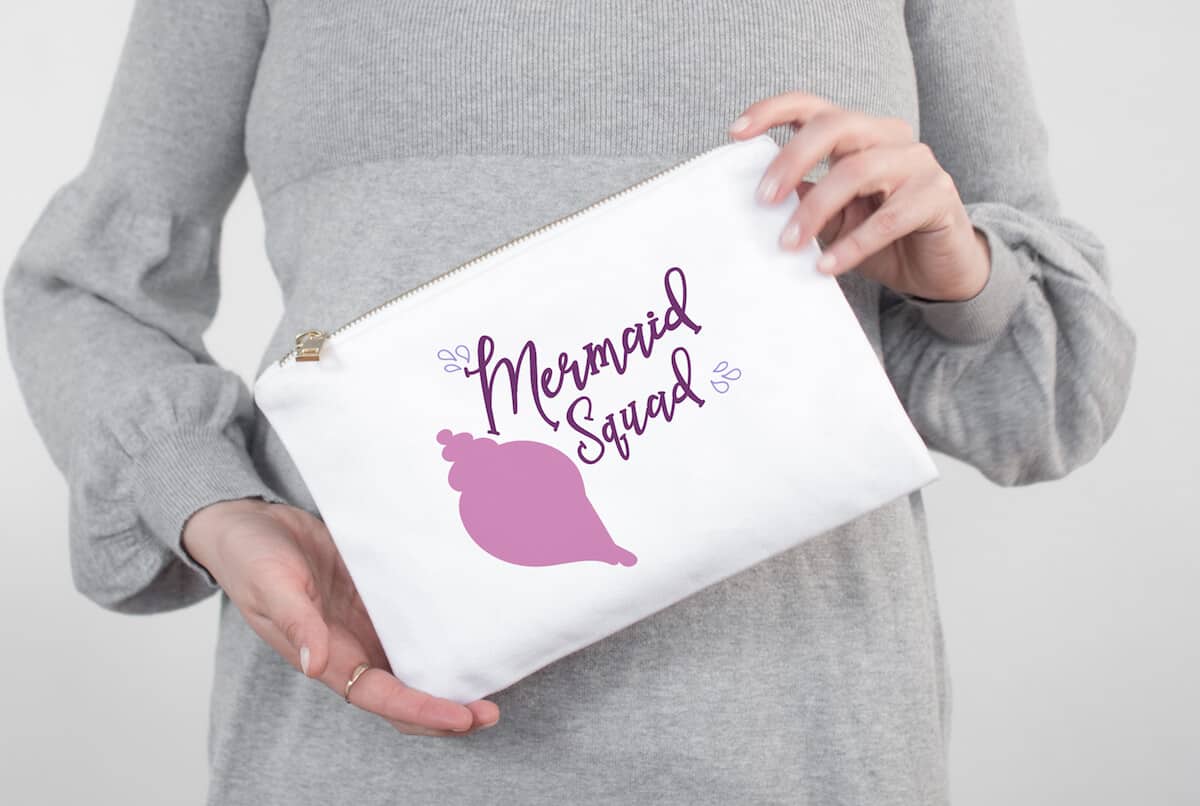 Mermaid Squad free cut file for silhouette on hand bag held by a lady in a grey dress in the background