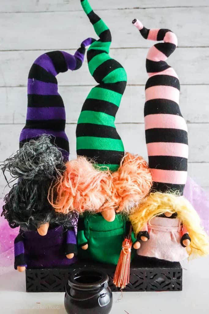 Three tall twisty hat girl gnomes on a white table representing the Sanderson Sisters from Hocus Pocus.