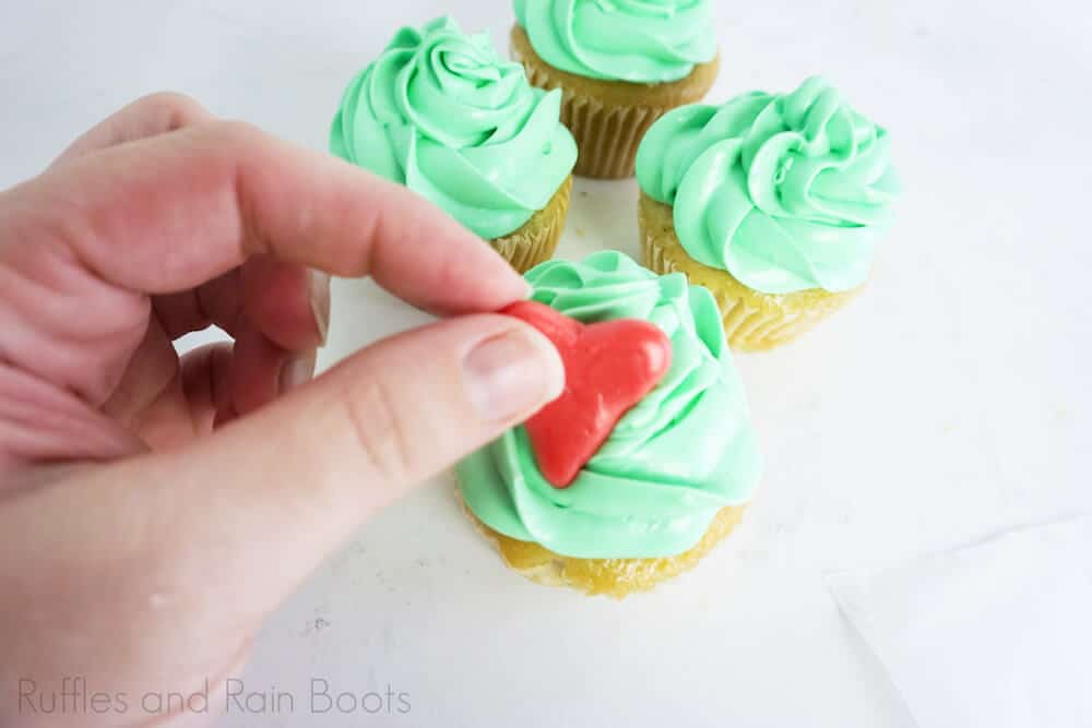 step 8 how to make grinch cupcakes by putting a candy heart on top