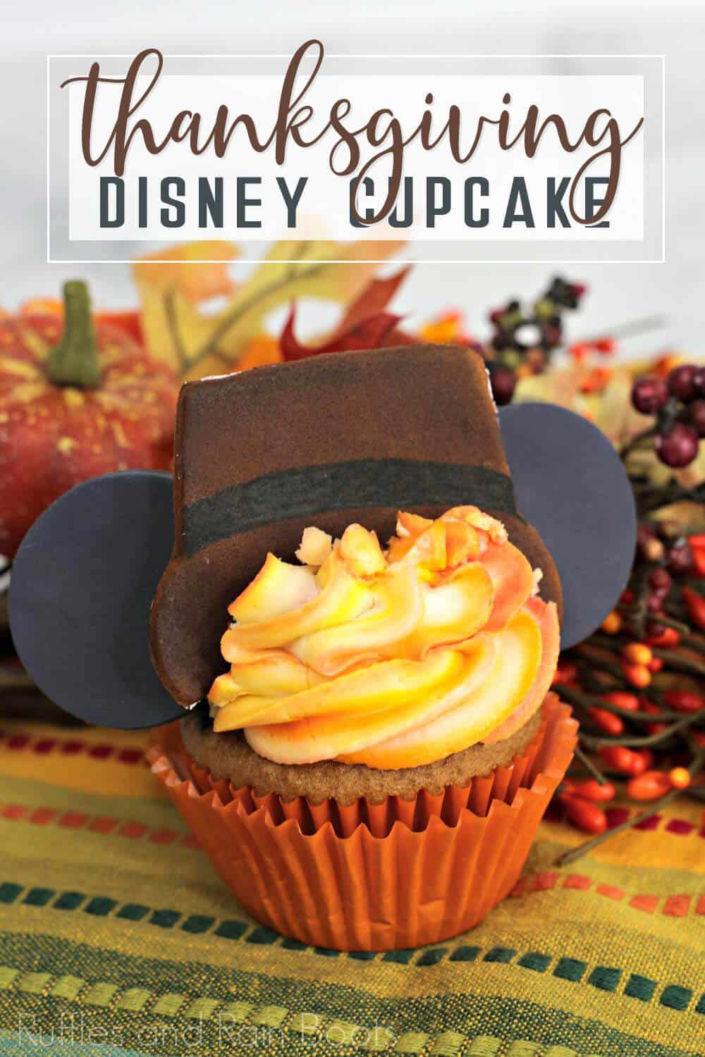 Spiced cake cupcake decorated like Mickey mouse pilgrim for Thanksgiving on napkin with fall pumpkin