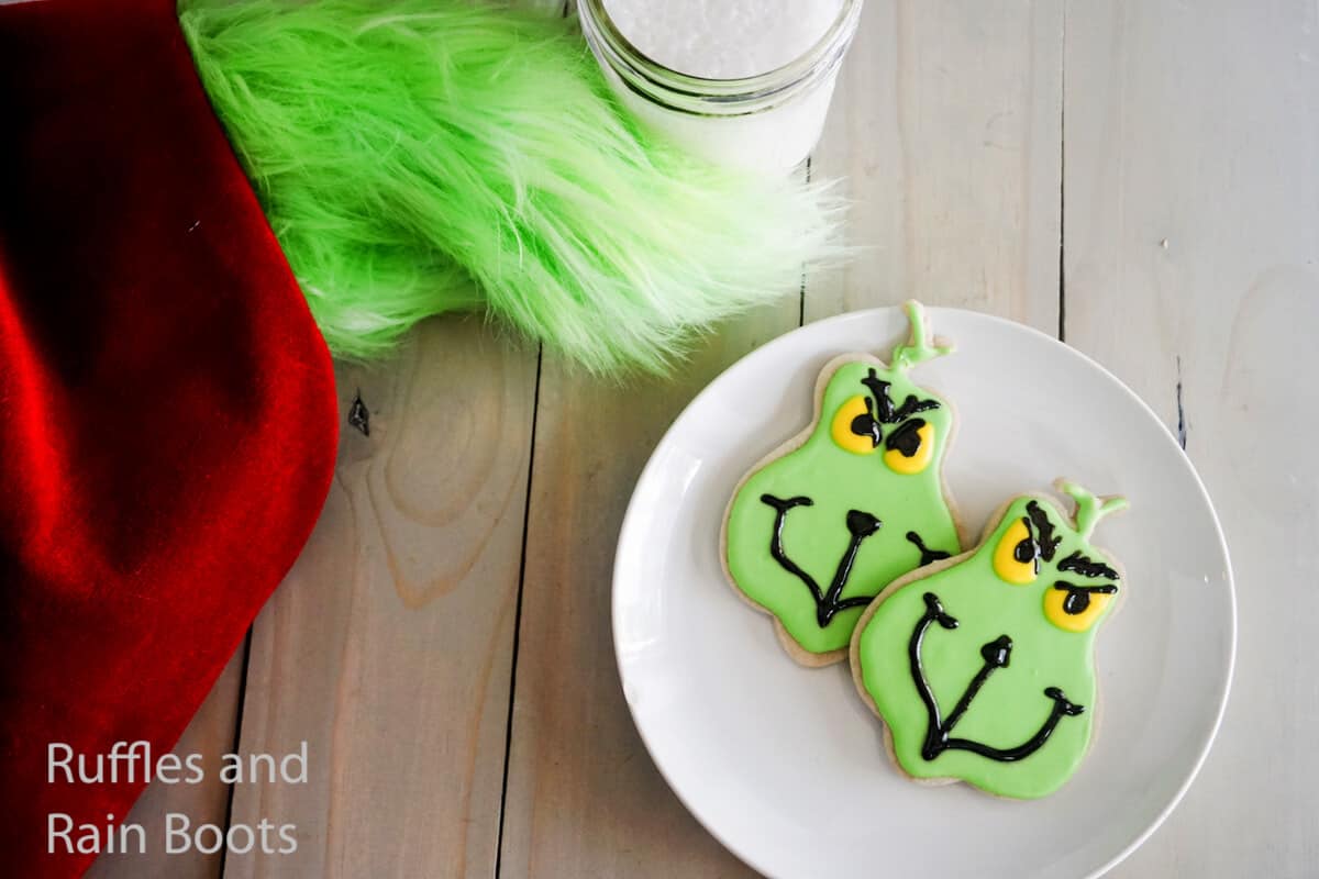 how to make grinch flood cookies on a white plate on a grey wood table
