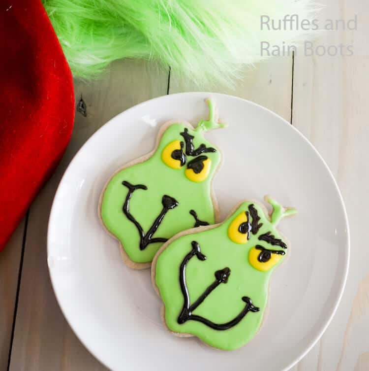 how to make grinch iced cookies on a white plate on a grey wood table