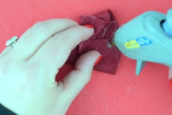Crafter using hot glue to create a felt gnome hat for ornaments.