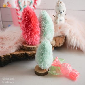 Colorful, fluffy yarn Christmas trees on a wooed base with a pink and teal holiday theme.