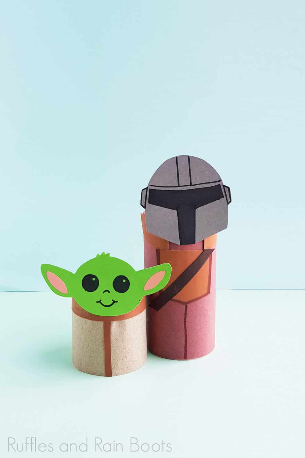 Vertical Image of finished Baby Yoda and the mandalorian paper craft on a light blue and green backgound