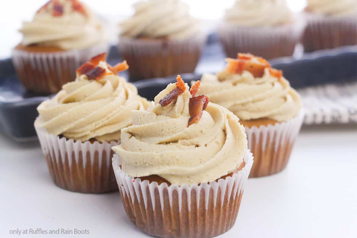 three easy maple bacon cupcakes on a white table