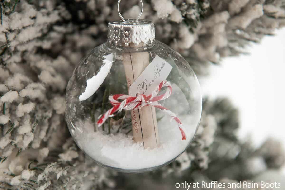 Horizontal image of an easy Christmas ornament craft with a letter to Santa, faux snow, and a bit of red twine.
