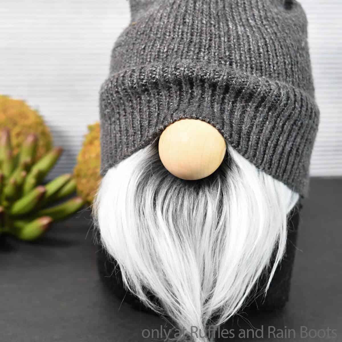 Close up of handmade gnome with a sock and. a sweater sleeve hat with large wooden nose.