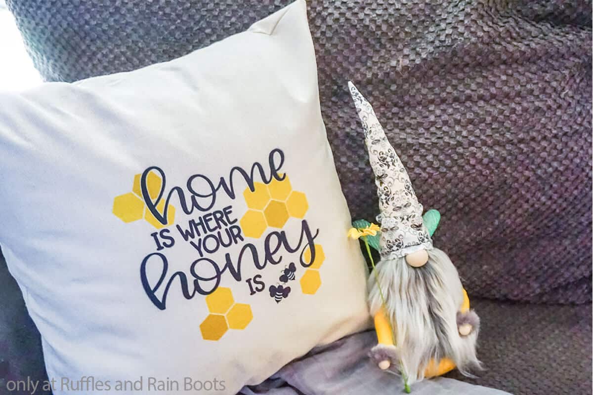 Horizontal image of a sublimation pillowcase craft sitting on a couch next to a bee gnome. 