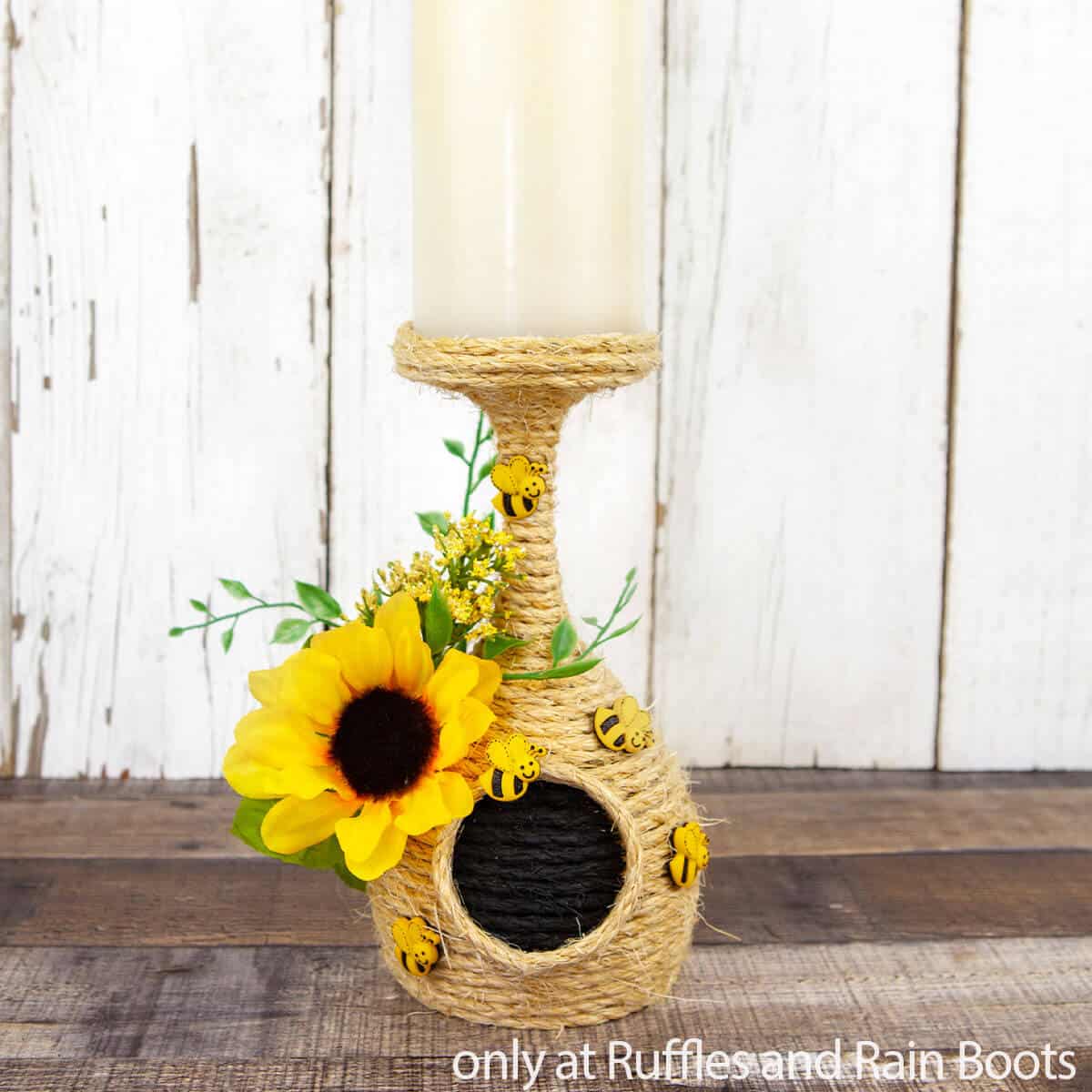 Vertical image of a Dollar Tree beehive candle holder craft on white wood background.