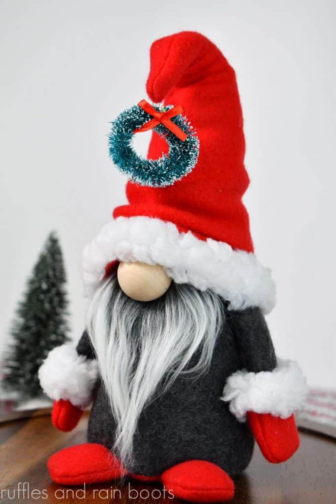 vertical image of a red white and gray Nordic gnome in Scandinavian style of a gnome with arms and legs in fleece and fur trim for Christmas